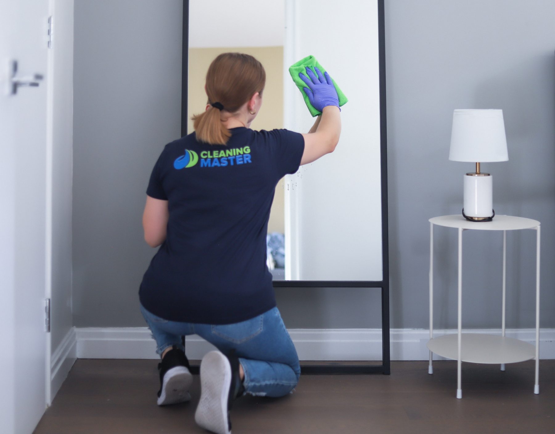 Cleaning Master professional polishing a full-length mirror in a bedroom
