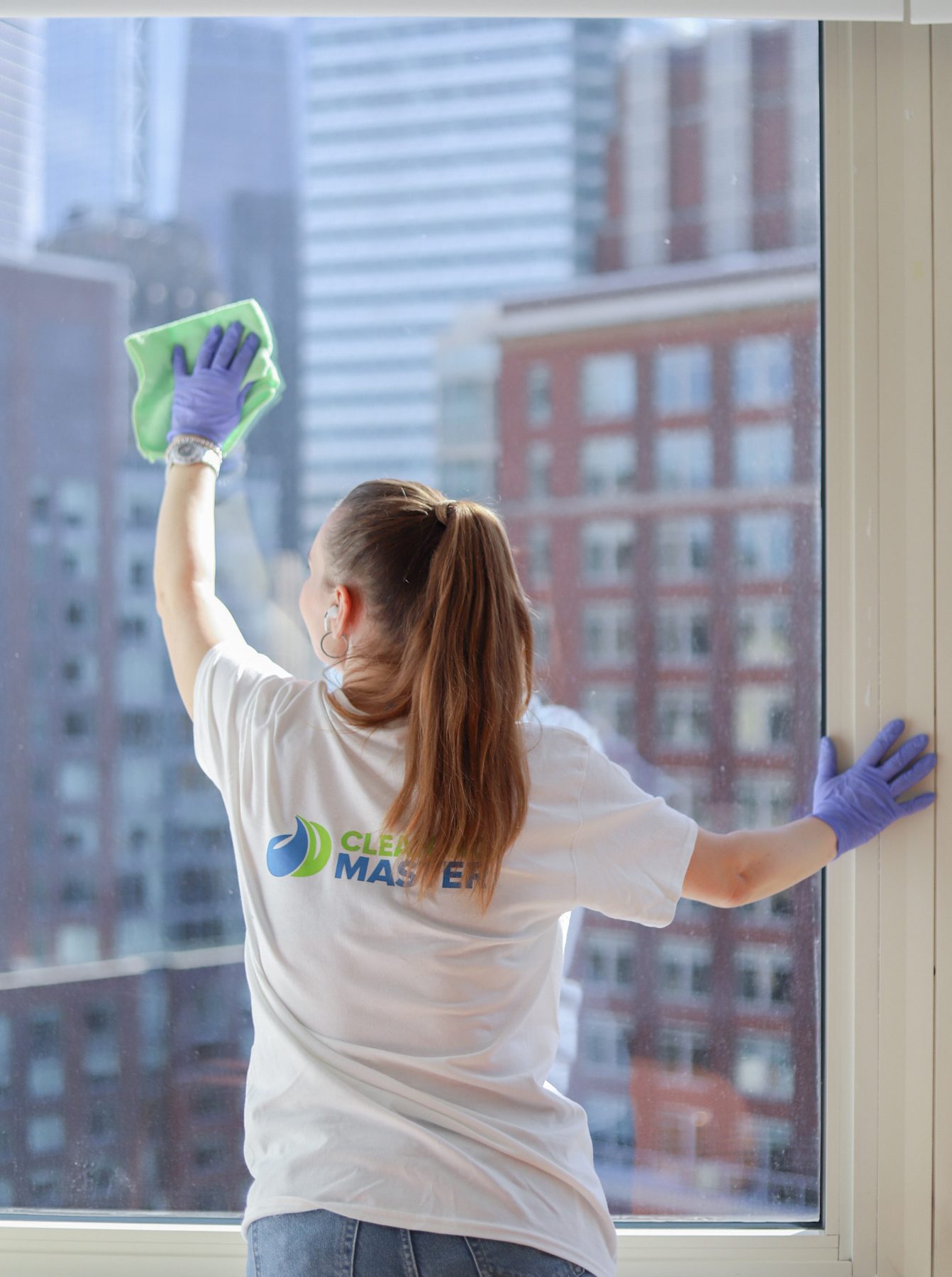 Cleaning Master professional cleaning a high-rise apartment window with the NYC skyline behind it