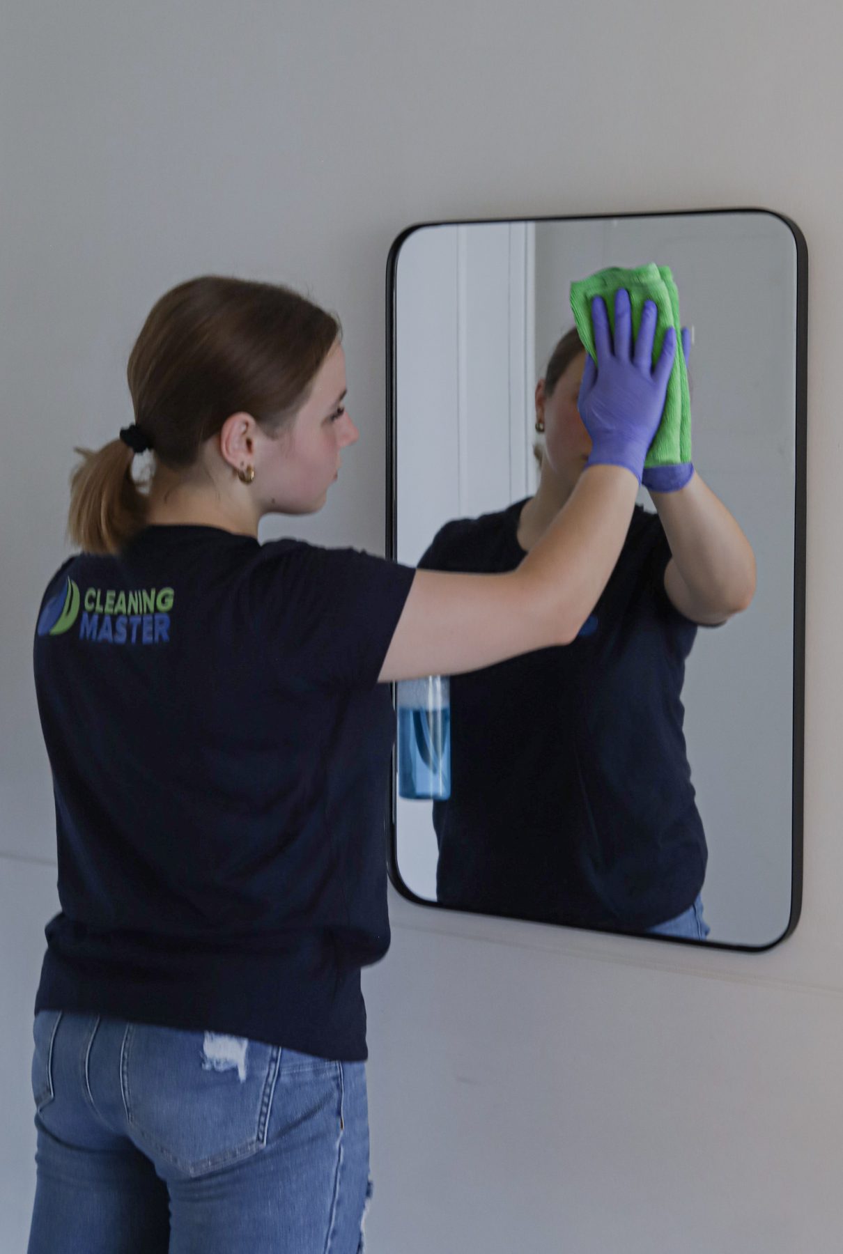 Cleaning Master professional cleaning a wall mirror in a fitness room