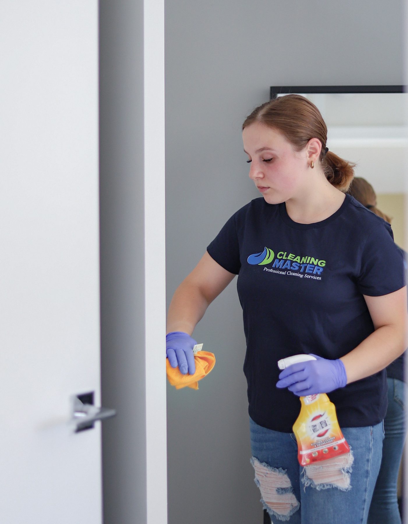 Cleaning Master professional in navy uniform moving between rooms with cleaning supplies