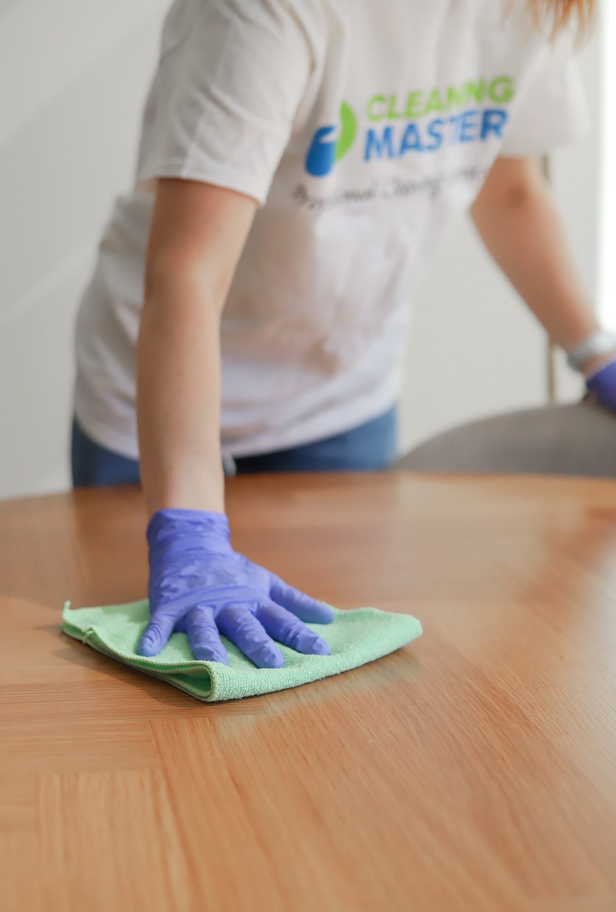 Close-up of a Cleaning Master professional wiping a wood surface with a microfiber cloth