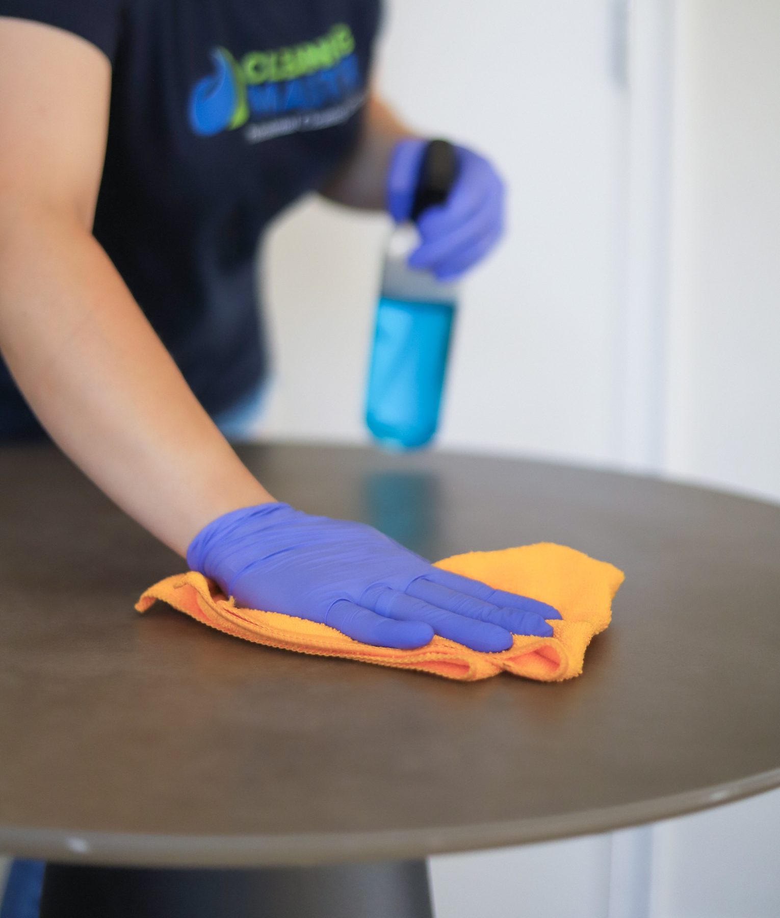 Cleaning Master professional sanitizing a retail display table with a spray bottle and cloth