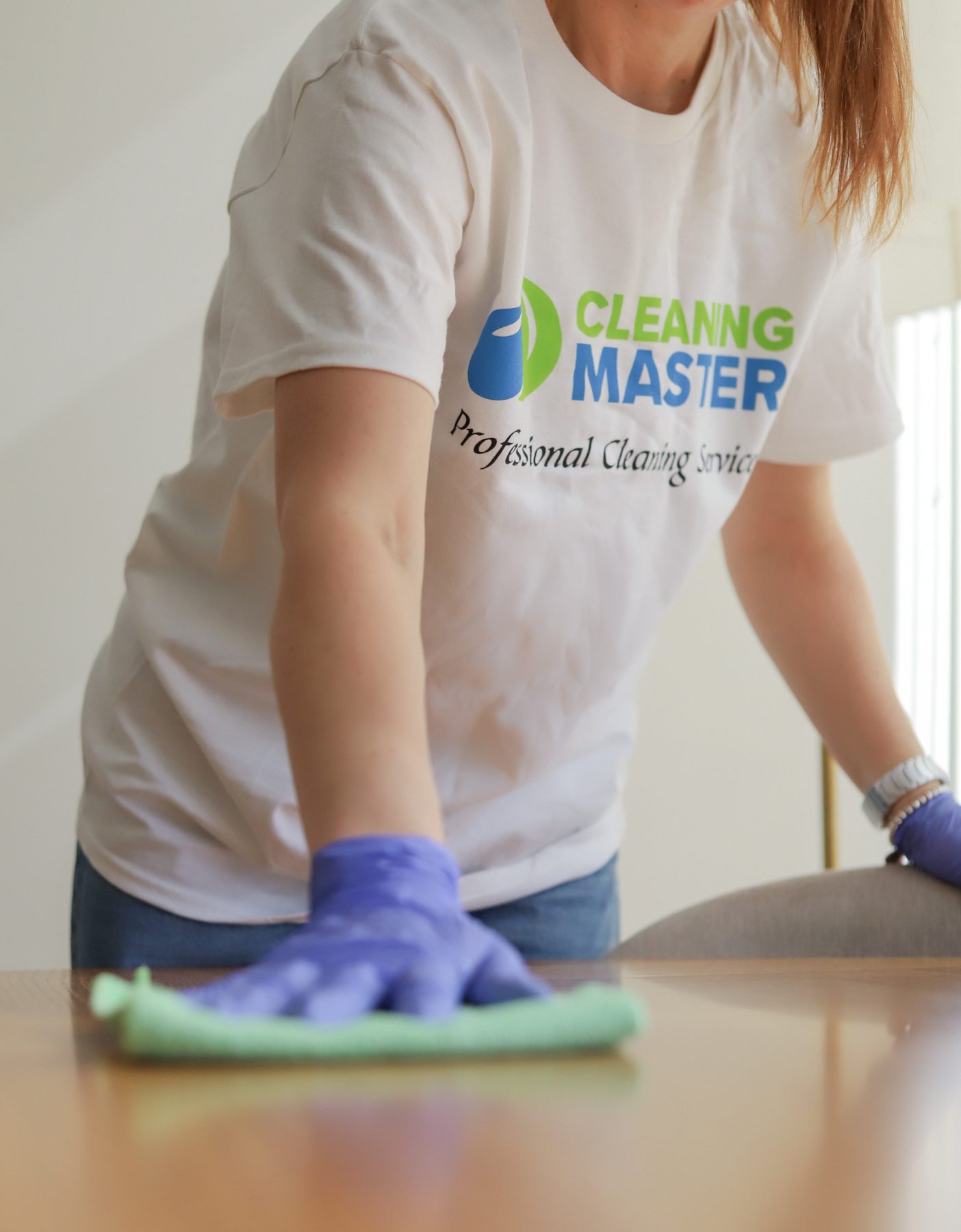 Cleaning Master professional in a branded shirt wiping a wooden table in a Brooklyn apartment