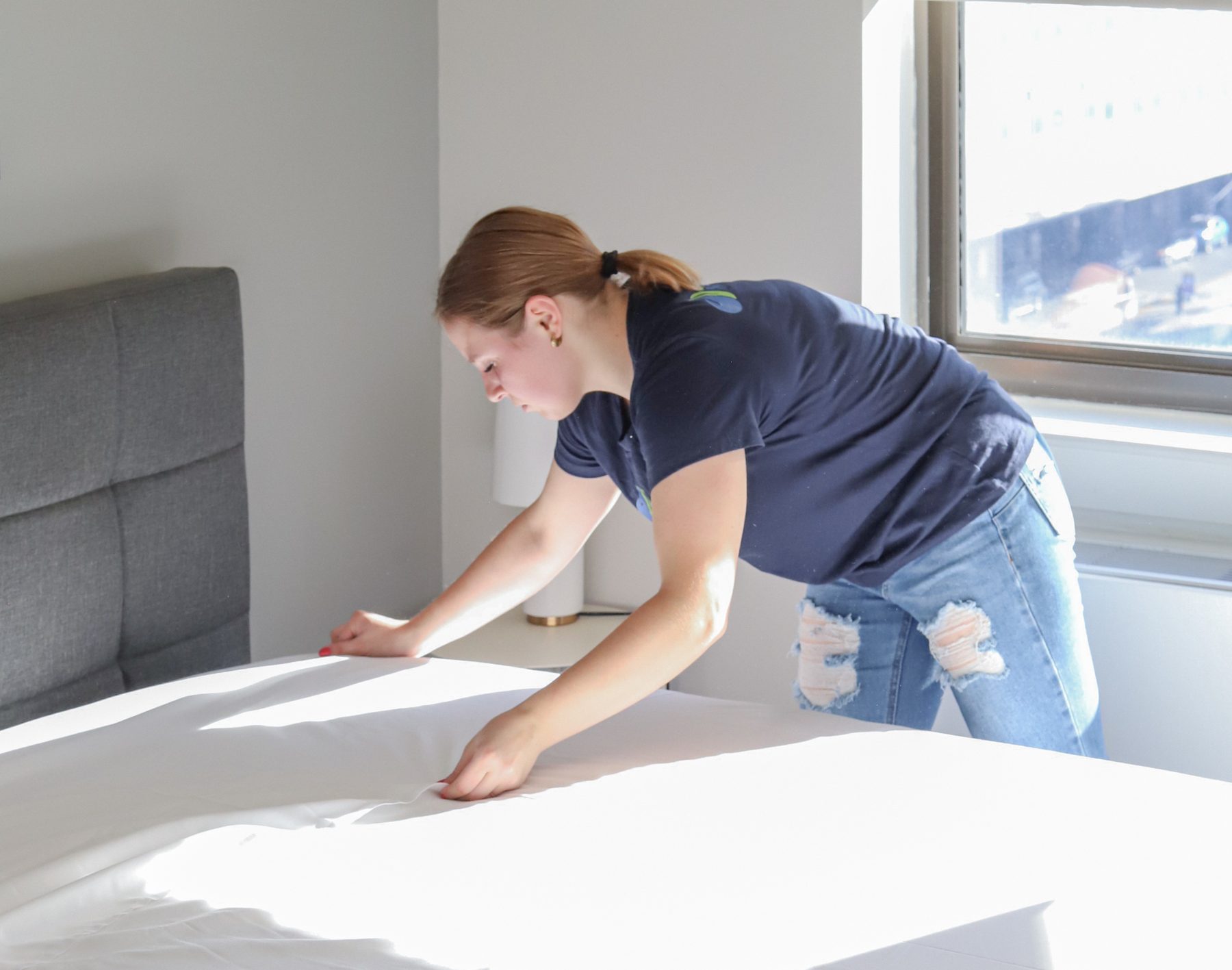 Cleaning Master professional changing bed linens in a hotel-style guest room